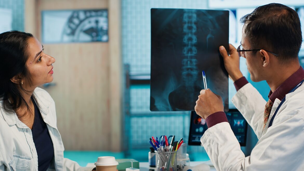 Indian healthcare expert sharing medical expertise with a patient in office, reviewing x ray scans and MRI diagnostics to focus on accurate treatment and recovery. Insurance consultation. Camera A.